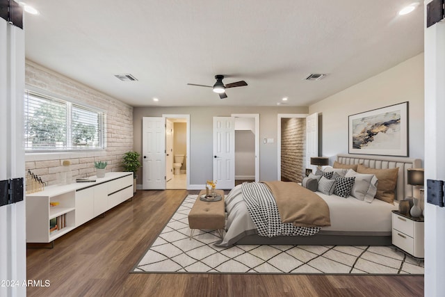 bedroom with connected bathroom, ceiling fan, brick wall, and wood-type flooring