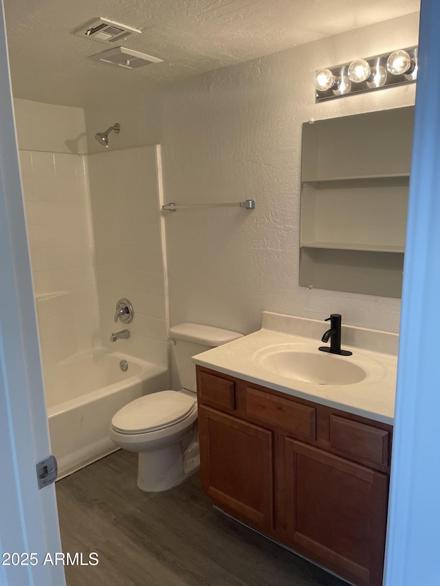 full bath with wood finished floors, toilet, vanity, a textured ceiling, and shower / bathtub combination