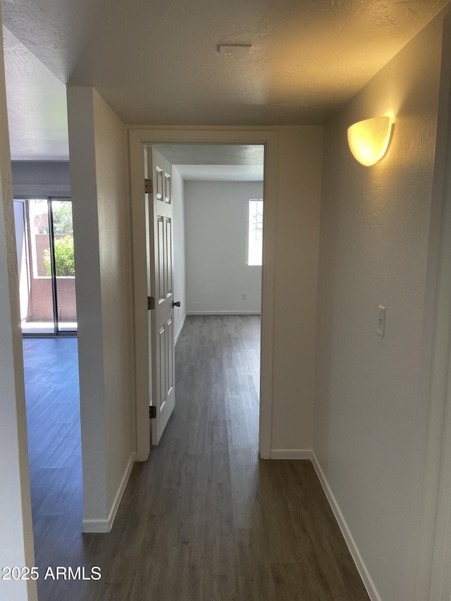 hall with dark wood-style flooring, baseboards, and a textured ceiling