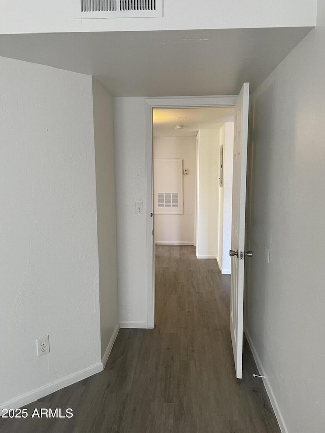 corridor featuring dark wood-style flooring and baseboards