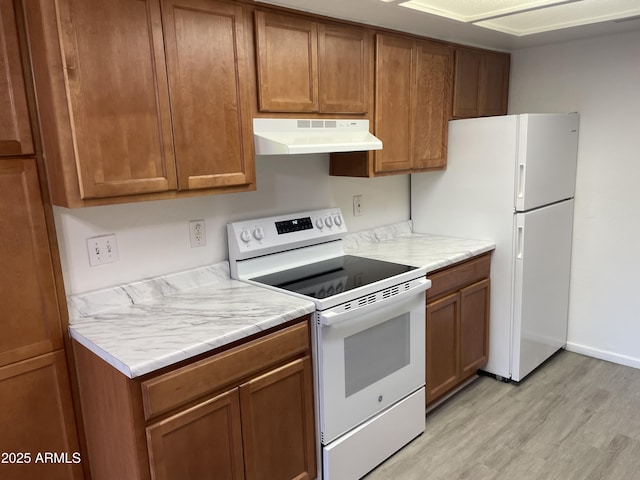 kitchen featuring under cabinet range hood, white appliances, light wood finished floors, and brown cabinetry