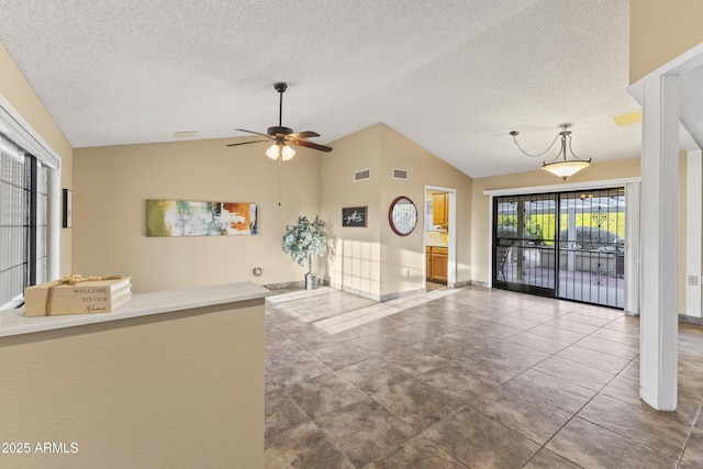 unfurnished living room featuring tile patterned flooring, ceiling fan, a textured ceiling, and vaulted ceiling