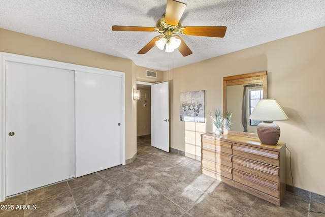 unfurnished bedroom with ceiling fan, a textured ceiling, and a closet