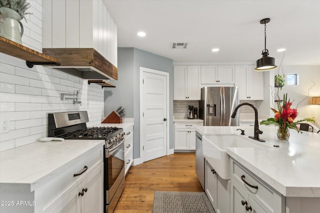 kitchen with pendant lighting, white cabinetry, stainless steel appliances, and light stone countertops