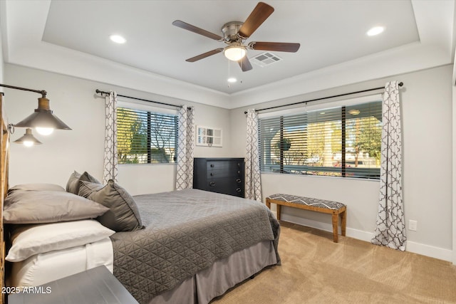 bedroom with ceiling fan, light colored carpet, and a raised ceiling