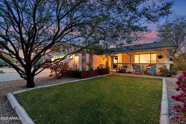 back house at dusk with a lawn