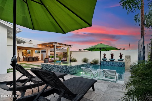 pool at dusk with a patio area, a hot tub, pool water feature, and a water view