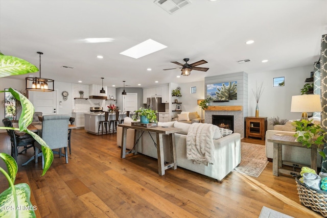 living room featuring ceiling fan with notable chandelier and hardwood / wood-style floors