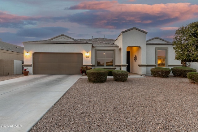 mediterranean / spanish-style house with a garage, concrete driveway, a tiled roof, and stucco siding