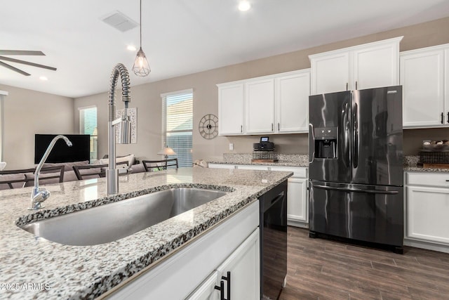 kitchen featuring light stone counters, visible vents, white cabinetry, a sink, and black appliances