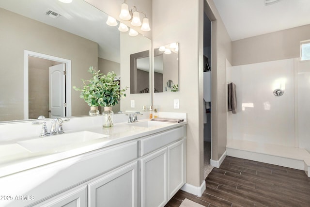 bathroom featuring double vanity, wood tiled floor, visible vents, and a sink