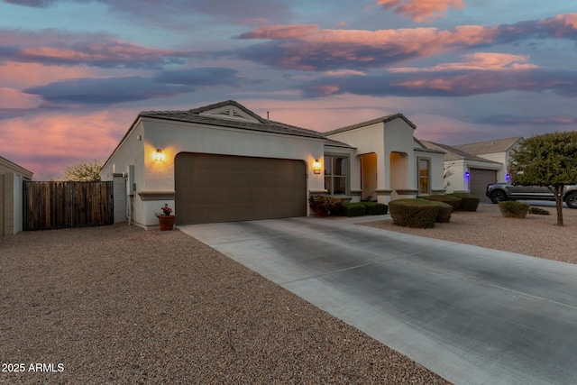 view of front of house with an attached garage, fence, concrete driveway, a gate, and stucco siding