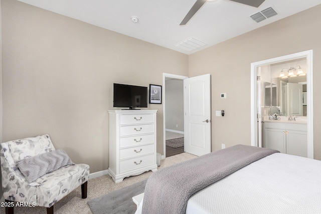 bedroom with baseboards, visible vents, light colored carpet, ensuite bath, and ceiling fan