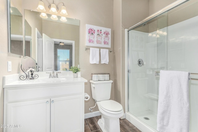 bathroom with baseboards, toilet, wood tiled floor, vanity, and a shower stall