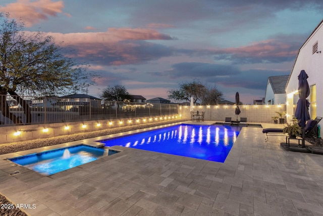 pool at dusk with an in ground hot tub, a patio area, a fenced backyard, and a fenced in pool