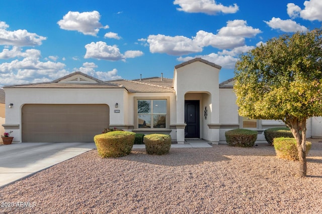 mediterranean / spanish-style home featuring a garage, a tiled roof, driveway, and stucco siding