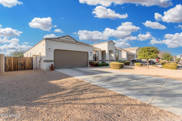 view of front of house featuring an attached garage, fence, driveway, a gate, and stucco siding