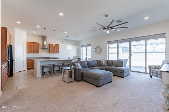 living room with ceiling fan, light colored carpet, and sink