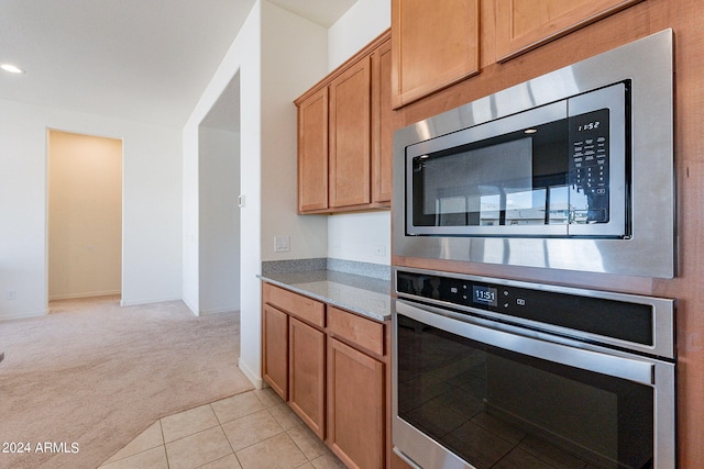 kitchen featuring light colored carpet, stainless steel appliances, and stone countertops