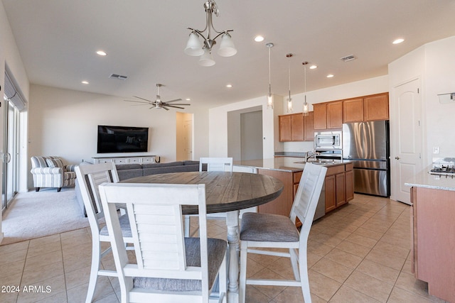 dining space with sink, light tile patterned flooring, and ceiling fan with notable chandelier