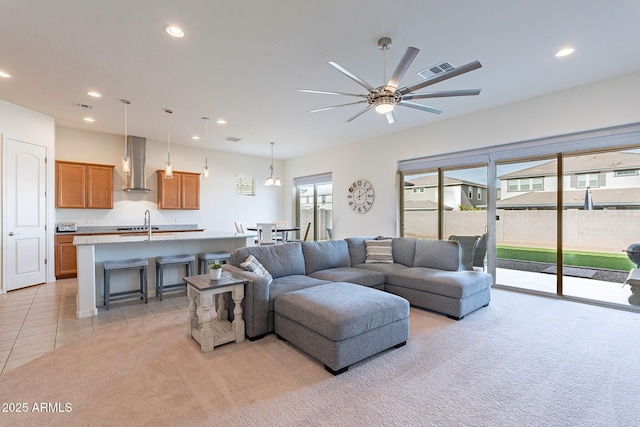 carpeted living room with ceiling fan and sink