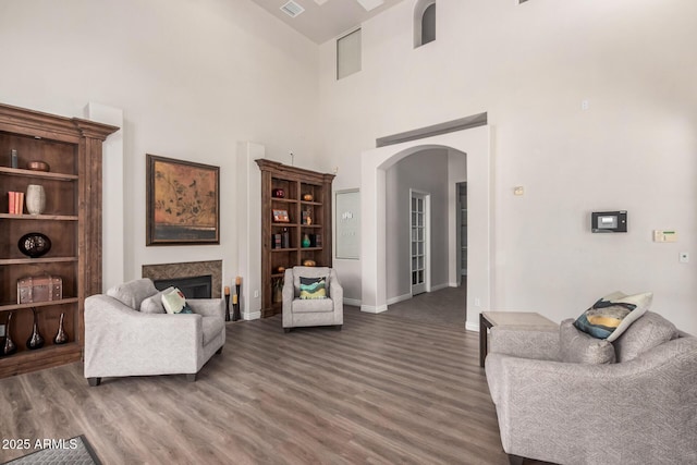 14575 W Mountain View Blvd Unit 12309, Surprise, AZ 85374 - living room featuring arched walkways, wood finished floors, a towering ceiling, and a fireplace