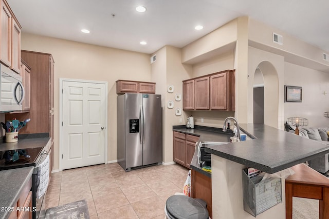 14575 W Mountain View Blvd Unit 12309, Surprise, AZ 85374 - kitchen with stainless steel appliances, a peninsula, dark countertops, a kitchen bar, and arched walkways