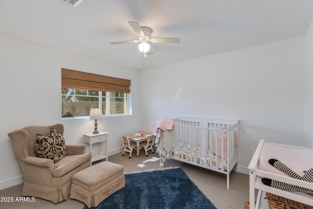 bedroom featuring a nursery area, carpet, a ceiling fan, and baseboards