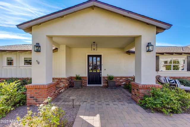 view of exterior entry with stucco siding and brick siding