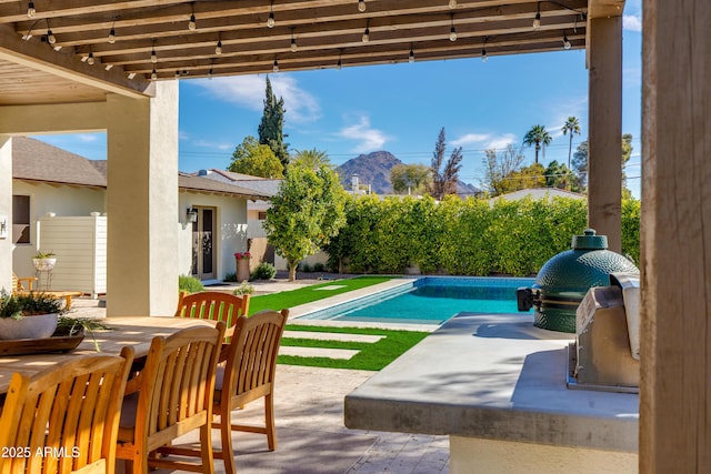 view of patio / terrace featuring an outdoor kitchen, a grill, fence, a fenced in pool, and outdoor dining space