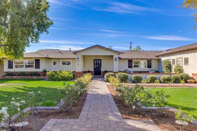 ranch-style home featuring a front lawn, brick siding, and stucco siding