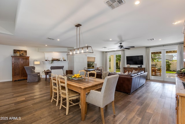 dining area featuring a brick fireplace, visible vents, dark wood-type flooring, and french doors