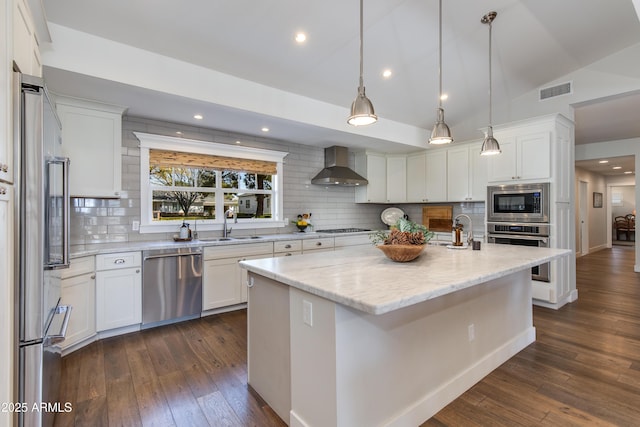 kitchen featuring lofted ceiling, appliances with stainless steel finishes, dark wood-type flooring, a sink, and wall chimney exhaust hood