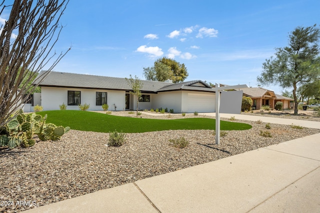 single story home featuring a garage, concrete driveway, a front yard, and stucco siding