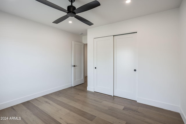 unfurnished bedroom with a closet, baseboards, wood finished floors, and recessed lighting