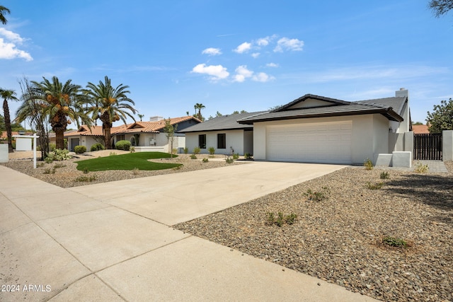 ranch-style house with a garage, concrete driveway, fence, and stucco siding