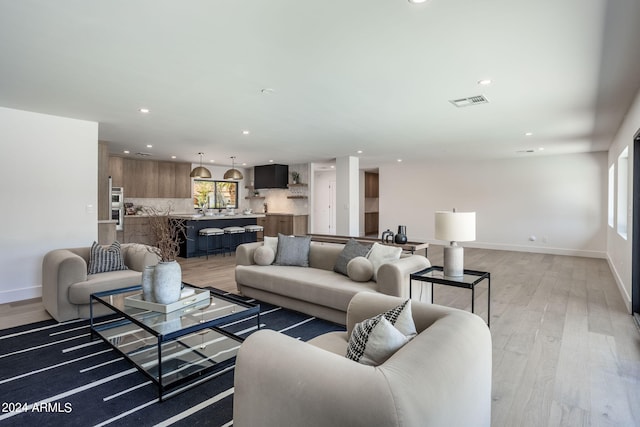 living room featuring light wood-style flooring, visible vents, baseboards, and recessed lighting