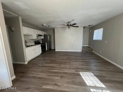 kitchen featuring ceiling fan, electric range, dark wood-type flooring, fridge, and white cabinets