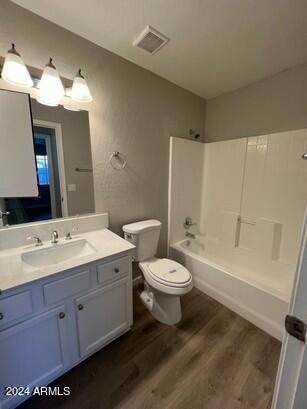 full bathroom with hardwood / wood-style flooring,  shower combination, vanity, and toilet