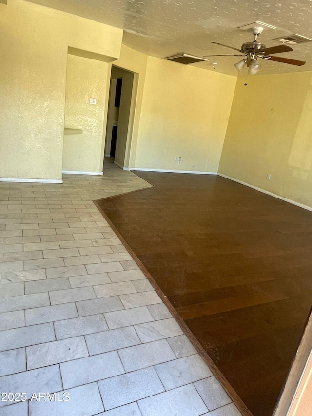 tiled empty room with a textured ceiling and ceiling fan