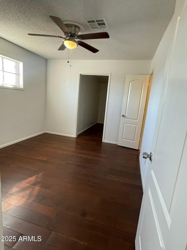 empty room featuring a textured ceiling, ceiling fan, and dark hardwood / wood-style floors