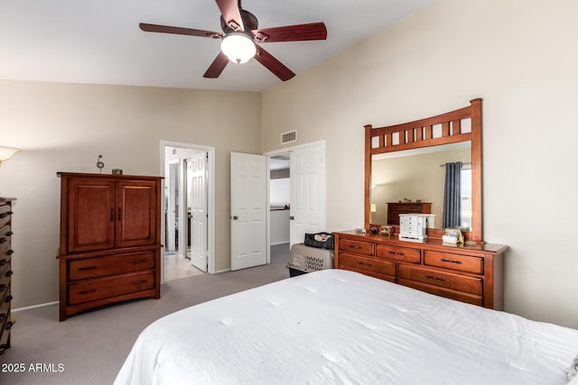 bedroom with vaulted ceiling, light carpet, ceiling fan, and ensuite bath