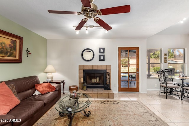 living room featuring ceiling fan, a fireplace, and light tile patterned floors