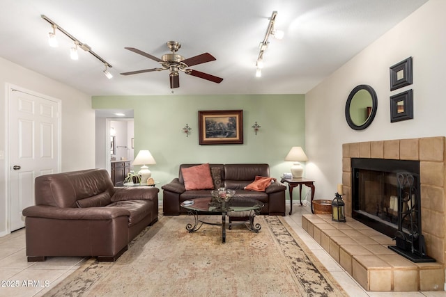 tiled living room featuring ceiling fan, a fireplace, and rail lighting