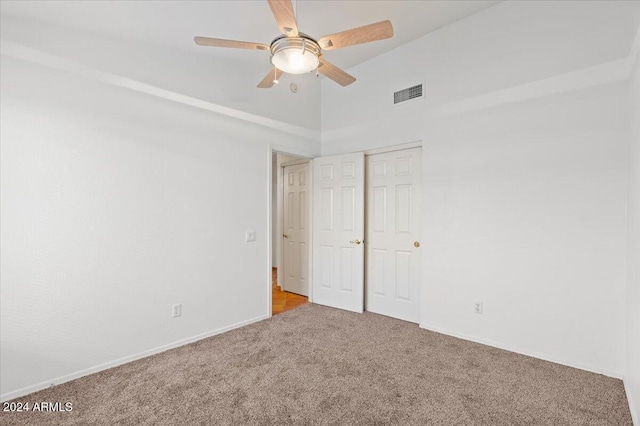 unfurnished bedroom featuring a closet, light colored carpet, high vaulted ceiling, and ceiling fan