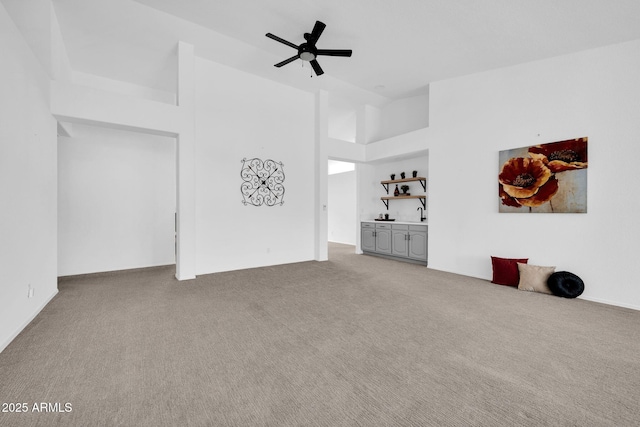 unfurnished living room featuring ceiling fan, high vaulted ceiling, and carpet