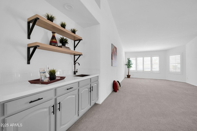 interior space with sink, light colored carpet, and white cabinets