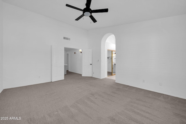 carpeted spare room with a high ceiling and ceiling fan