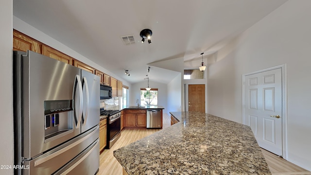 kitchen featuring sink, vaulted ceiling, dark stone counters, pendant lighting, and stainless steel appliances