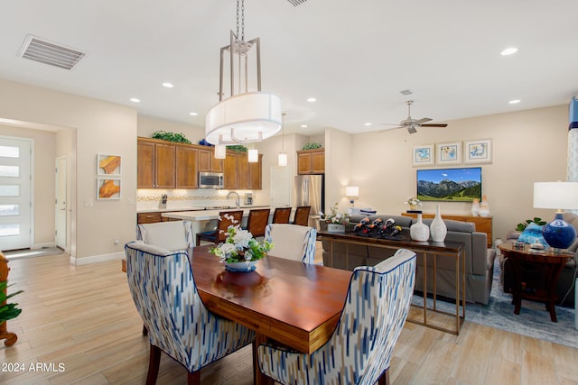 dining space featuring ceiling fan, sink, and light hardwood / wood-style flooring